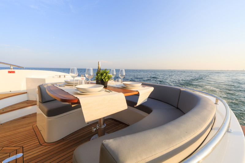 Mesa de comedor elegante en la cubierta de un barco con vistas al mar al atardecer en Cerdeña.