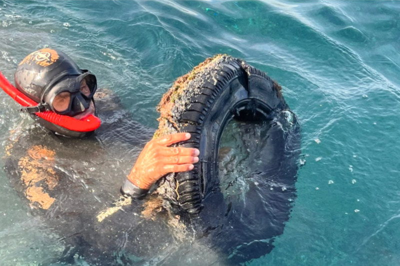 Buceador sacando un neumático del mar