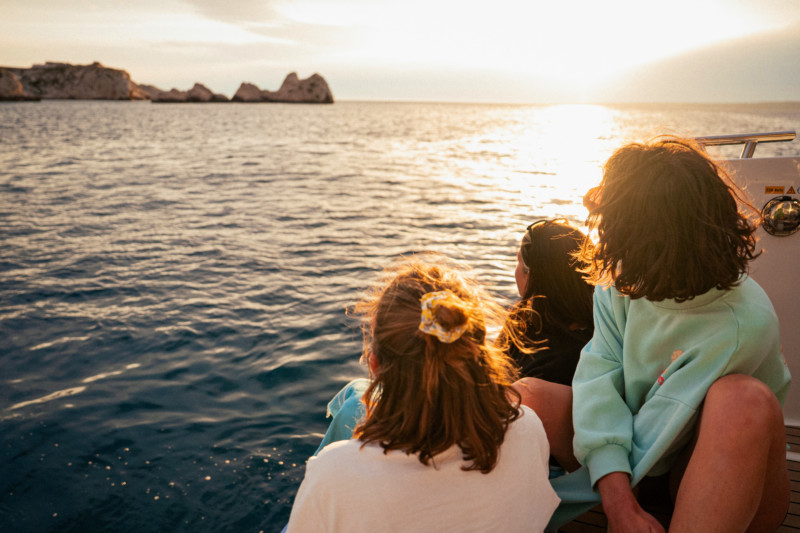 Personas viendo la puesta de sol desde un barco